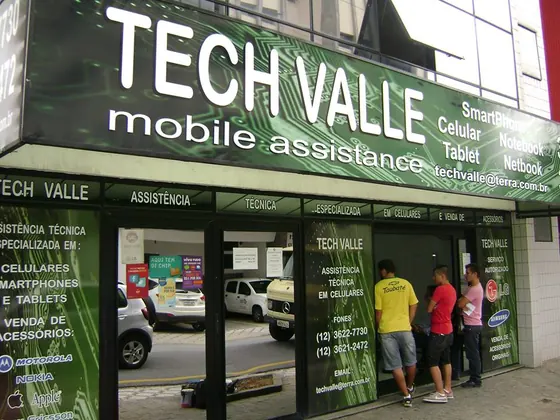 Fachada de loja de assistência técnica com letreiro e adesivos de vitrine